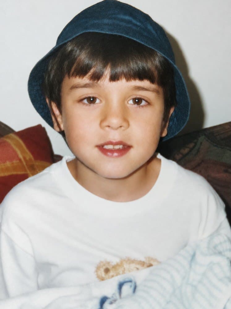 Rodrigo as a young boy in a navy bucket hat