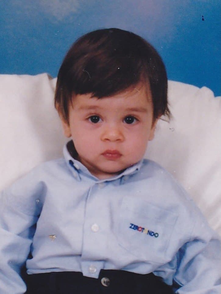 Rodrigo as a toddler in a pale blue shirt, in a studio portrait