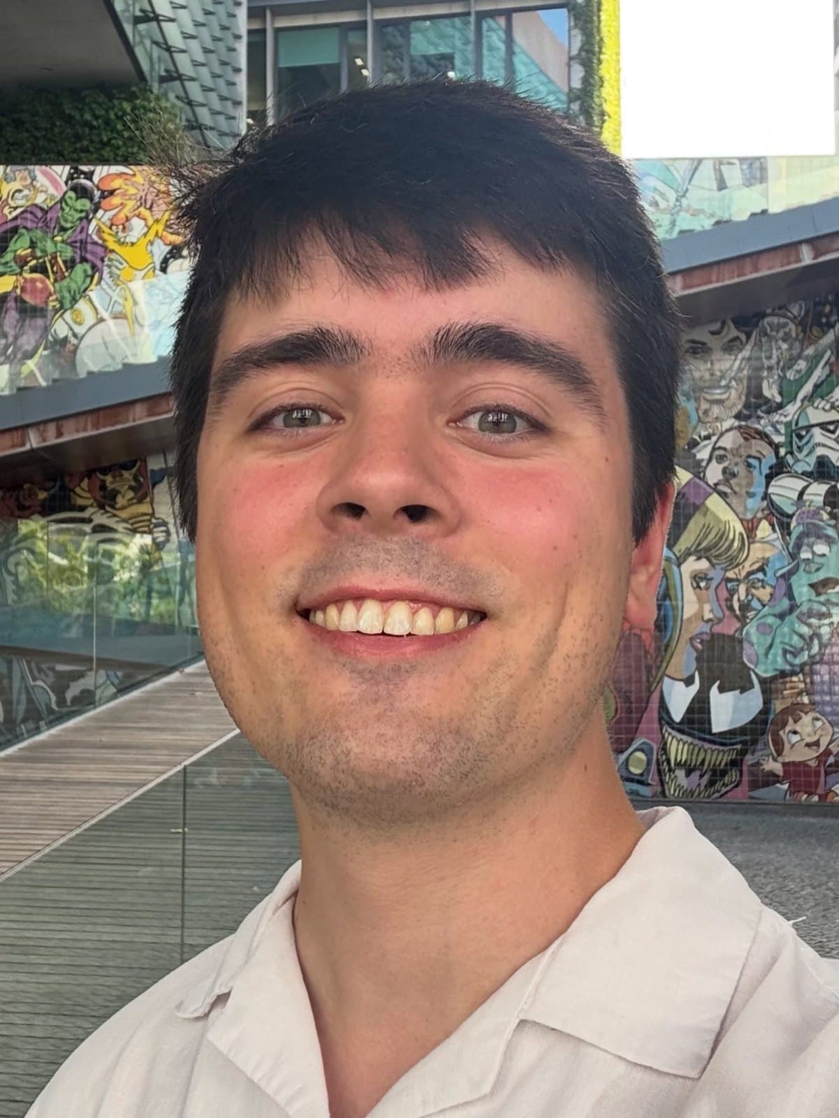 Rodrigo smiling in front of a comic-book mural of superheroes